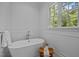 Bright bathroom featuring a soaking tub with a window view and stylish wooden stool at 387 Riverstone Dr, Pittsboro, NC 27312