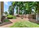 Shot of a fenced backyard, featuring a grassy lawn, mulch landscaping, and mature trees at the property at 412 Whitt Ave, Burlington, NC 27215