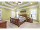 Comfortable bedroom featuring a tray ceiling, ceiling fan, carpet, and natural lighting at 412 Whitt Ave, Burlington, NC 27215