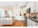 Well-lit kitchen boasts stainless steel appliances, an island, and classic white cabinets at 412 Whitt Ave, Burlington, NC 27215