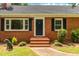 Inviting brick home entrance with blue door, black shutters, and manicured landscaping at 4703 Pleasant Green Rd, Durham, NC 27705