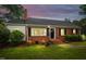 Charming brick home featuring a manicured lawn, front garden, and a welcoming entrance at dusk at 4703 Pleasant Green Rd, Durham, NC 27705