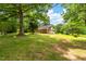 Scenic front yard with a lush, green lawn, mature trees, and a charming brick house at 4703 Pleasant Green Rd, Durham, NC 27705
