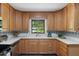 Kitchen with stainless steel appliances, wood cabinets, tile backsplash, and a bright window overlooking the yard at 4703 Pleasant Green Rd, Durham, NC 27705
