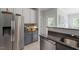 Modern kitchen with stainless steel refrigerator, gray lower cabinets, and light tiled floors at 500 Weaver Mine Trl, Chapel Hill, NC 27517