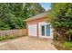 A detached garage with white doors and a concrete driveway is fenced in and surrounded by trees at 5405 Doemont Dr, Apex, NC 27539