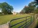 Large backyard with green grass, garden plots, and a storage shed, secured with a black metal fence at 56 Sugarhill Dr, Zebulon, NC 27597