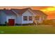 Charming single-story home with a well-manicured lawn and red garage door, bathed in a beautiful sunset at 56 Sugarhill Dr, Zebulon, NC 27597