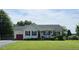 Charming one-story home features a welcoming front porch and well-manicured lawn, red garage door, and black shutters at 56 Sugarhill Dr, Zebulon, NC 27597
