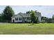 Charming home with well-kept lawn features a welcoming front porch, black shutters, and mature shade tree in the front yard at 56 Sugarhill Dr, Zebulon, NC 27597