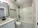 Bathroom with white marble-look floor tiles, black hardware, and a shower-tub combo with shelving at 608 E Umstead St, Durham, NC 27701
