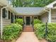Inviting front entrance with brick steps and lush greenery leading to a black front door with sidelights at 6605 Huntingridge Rd, Chapel Hill, NC 27517