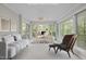 Bright sunroom features large windows, comfortable seating, and a dedicated workspace with a modern desk and chair at 6605 Huntingridge Rd, Chapel Hill, NC 27517