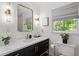 Bathroom vanity with modern mirror, dark cabinets, and toilet at 7016 Valley Dr, Raleigh, NC 27612