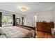 Well-lit bedroom with hardwood floors, dresser, and a view to the outside at 7016 Valley Dr, Raleigh, NC 27612