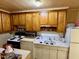 Compact kitchen featuring wooden cabinets, white appliances, and tiled backsplash at 981 Leasburg Rd, Roxboro, NC 27573