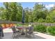 Spacious backyard featuring an outdoor dining area with a patio umbrella and wooded backdrop at 1154 Yorkshire Dr, Burlington, NC 27215
