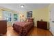 Bedroom with yellow walls, wood floors, windows with outside view, and a queen bed with burgundy bedspread at 116 Lost Tree Ln, Cary, NC 27513
