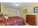 Bedroom featuring yellow walls, wood floors, queen bed with burgundy bedspread, and a wooden dresser at 116 Lost Tree Ln, Cary, NC 27513