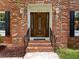 Close up of the front door to a brick home with black shutters and manicured yard at 116 Lost Tree Ln, Cary, NC 27513