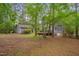 Spacious backyard with mature trees, a detached garage, and a small storage shed at 1302 Valley Run Dr, Durham, NC 27707