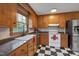 Functional kitchen featuring wooden cabinets, black and white checkered flooring, and stainless steel appliances at 1302 Valley Run Dr, Durham, NC 27707