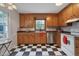 A functional kitchen showcasing wooden cabinetry, black and white checkered flooring, and stainless steel appliances at 1302 Valley Run Dr, Durham, NC 27707