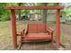 Exterior view of a weathered, wooden swing set sitting in a wooded backyard setting, offering a place to relax at 1401 Robinhood Rd, Durham, NC 27701