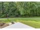 Well-maintained backyard with green grass, trees, and a concrete patio area for outdoor enjoyment at 160 Chandler Springs Dr, Holly Springs, NC 27540