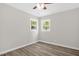 Bedroom with hardwood floors, fresh paint, ceiling fan, and two windows at 1605 Nixon St, Durham, NC 27707