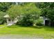 Cozy yellow home surrounded by lush greenery, offering a serene and private setting at 212 Plum St, Burlington, NC 27215