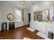 Bright bathroom featuring dual sinks with storage, a round mirror, and hardwood floors at 301 W Thorndale Dr, Oxford, NC 27565