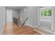 Bright hallway features hardwood floors, staircase, and door leading to carpeted room with lots of windows at 310 Hidden Lake Dr, Youngsville, NC 27596