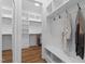 Walk-in closet featuring custom shelving, hanging rods, hooks, bench with storage, and wood flooring at 310 Hidden Lake Dr, Youngsville, NC 27596