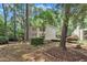 View of backyard with white brick and siding, mature trees and wood privacy fence at 3205 Dell Dr, Raleigh, NC 27609