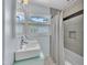 Bright bathroom with double sinks, large window, and tiled shower/bath at 3205 Dell Dr, Raleigh, NC 27609