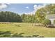 Spacious backyard with ample green space, lush mature trees, and a rustic wooden deck at 3679 Oak Lawn Farm Rd, Oxford, NC 27565