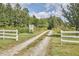 Long gravel driveway leading to Oxford Oaks property, framed by white fencing and lush greenery at 3679 Oak Lawn Farm Rd, Oxford, NC 27565