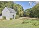 Exterior view of an outbuilding with light colored siding and a metal roof surrounded by green grass at 3679 Oak Lawn Farm Rd, Oxford, NC 27565