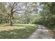 View of gravel driveway, large mature trees and manicured lawn at 3679 Oak Lawn Farm Rd, Oxford, NC 27565