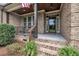 Inviting front porch featuring brick columns, wood ceiling, and a decorative glass front door at 3728 Marwick Ct, Wendell, NC 27591