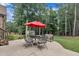 Cozy patio with outdoor seating under a red umbrella, surrounded by lush greenery and serene wooded scenery at 3728 Marwick Ct, Wendell, NC 27591