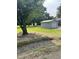 Lawn view of the outbuilding with a roll up door, next to a house on a large green lot with mature trees at 40 Bait Rd, Dunn, NC 28334