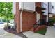 Exterior view of a brick building with a white door, black railing, and landscaped surroundings at 400 W Rosemary St # 114, Chapel Hill, NC 27516