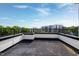 Spacious roof deck with black metal railing offering views of nearby buildings and blue skies at 400 W Rosemary St # 114, Chapel Hill, NC 27516