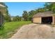 View of the detached garage and backyard, showing mature trees, lush grass and sunny sky at 407 Hillcrest Ave, Burlington, NC 27215