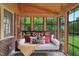 Relaxing porch swing with throw pillows is surrounded by a brick wall and large windows with backyard views at 407 Hillcrest Ave, Burlington, NC 27215