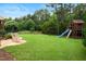 Expansive backyard with lush lawn, mature trees, and a playset area with swing and slide at 4729 Adler Pass, Raleigh, NC 27612
