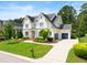 Stately two-story home showcasing a manicured lawn, charming front porch, and a three-car garage at 4729 Adler Pass, Raleigh, NC 27612