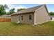 The backyard features a grassy area and a simple exterior of the house with beige siding and a door at 5081 Pioneer Dr, Sanford, NC 27330